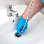 Bingham Plumbing & Gas - A plumber's hand using a tool to unclog a sink, demonstrating effective drain cleaning.