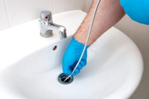 Bingham Plumbing & Gas - A plumber's hand using a tool to unclog a sink, demonstrating effective drain cleaning.